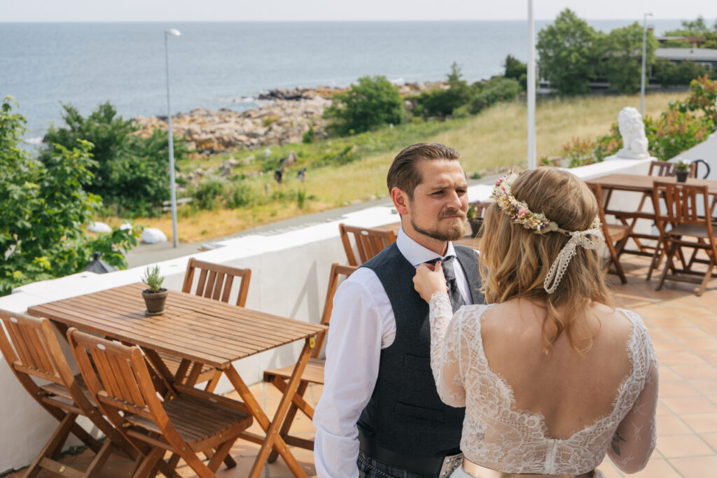 A bride checking grooms tie before their intimate wedding abroad in Bornholm island in Scandinavia