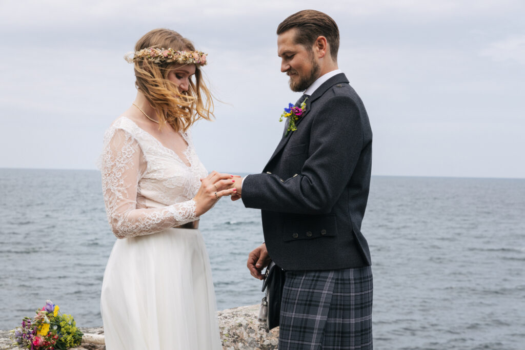 A couple are exchanging rings at their elopement wedding in Europe, in Bornholm island