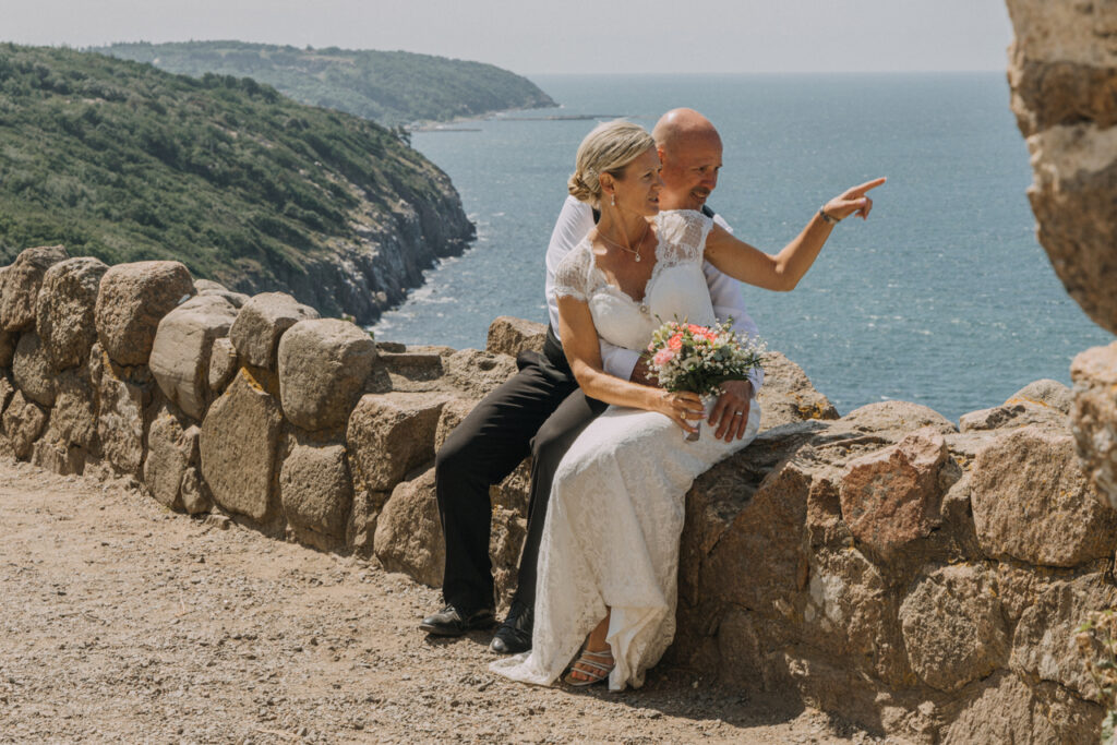 Newlyweds sitting at the Hammershus Ruins enjoying their adventurous wedding destination in Europe.