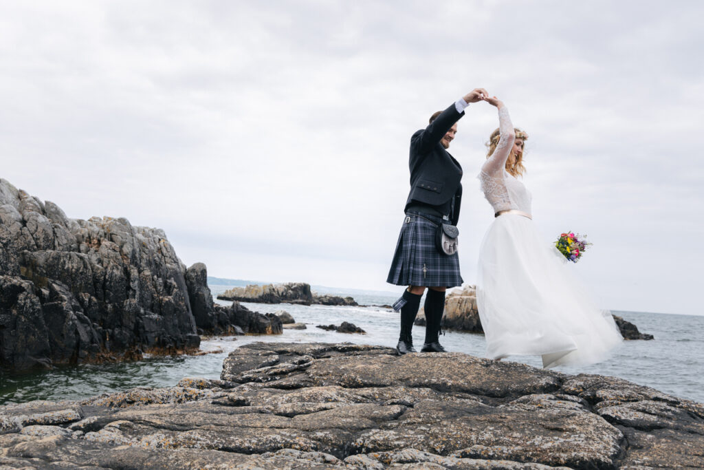 Newlyweds dancing on the rock of Bornholm island, where they have all inclusive elopement for two.