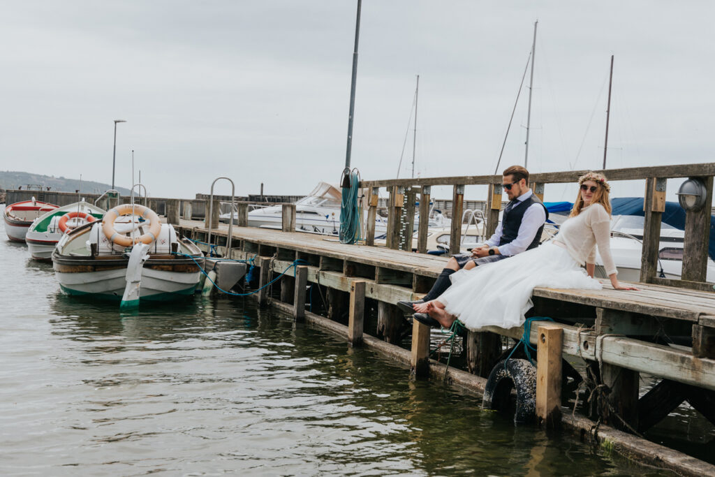 Newlyweds are sitting on the pierce during their elopement wedding in Denmark.