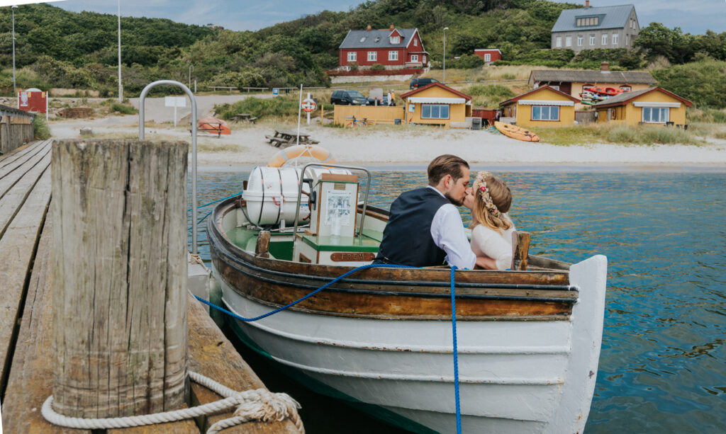 Newlyweds are kissing in the boat, as they just got married abroad in Bornholm island.