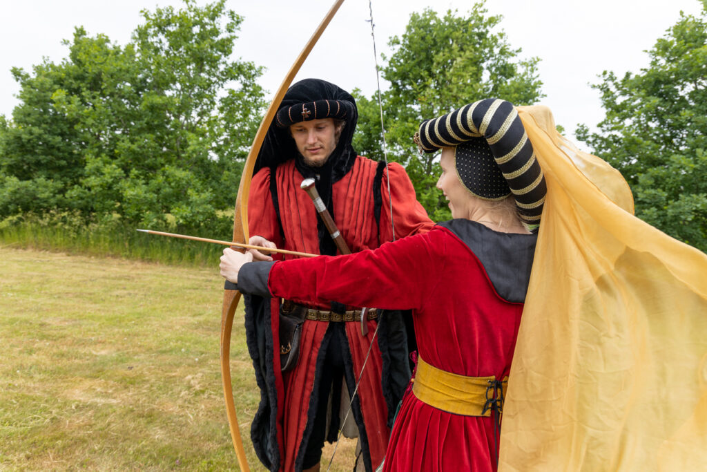 Newlyweds enjoying archery after their historical wedding in the medieval style at Bornholm’s Middle Age Center, a perfect venue for unusual weddings abroad.