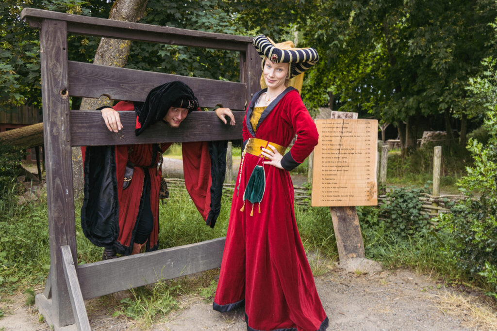 A bride and groom dressed in historical fashion enjoying games at the Middle Ages Center in Bornholm Island during their unusual medieval wedding, a perfect elopement abroad idea.