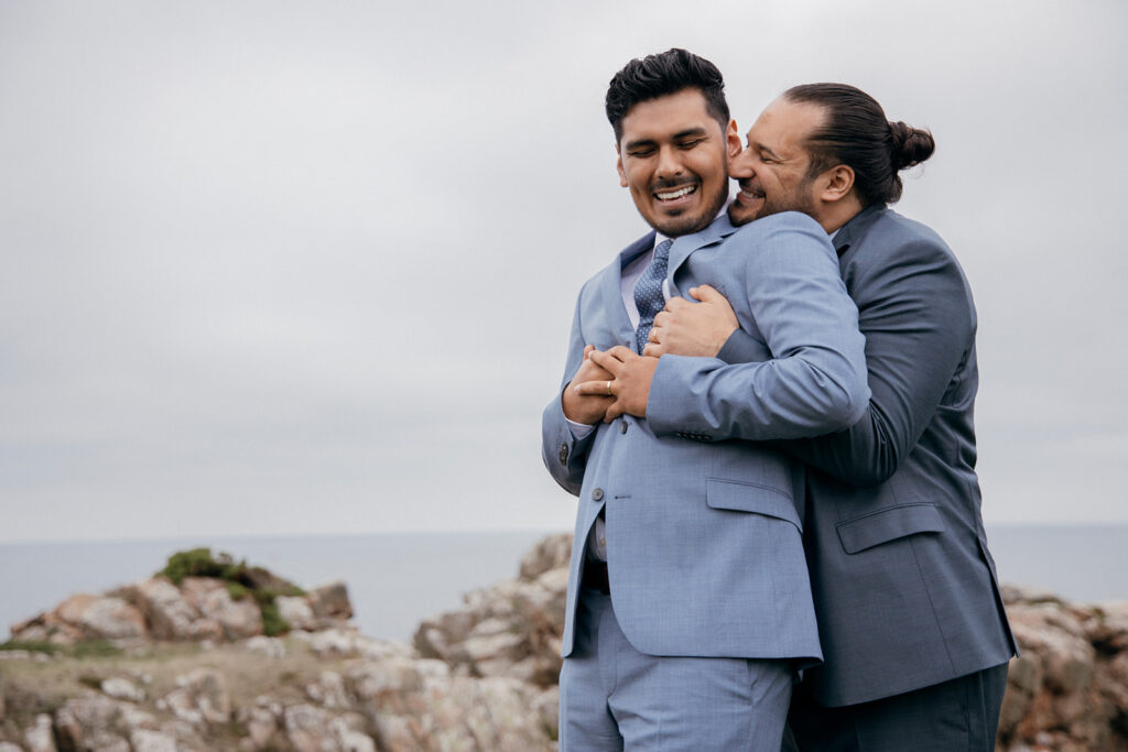Two gays embracing by the sea during their micro wedding on Bornholm Danish island