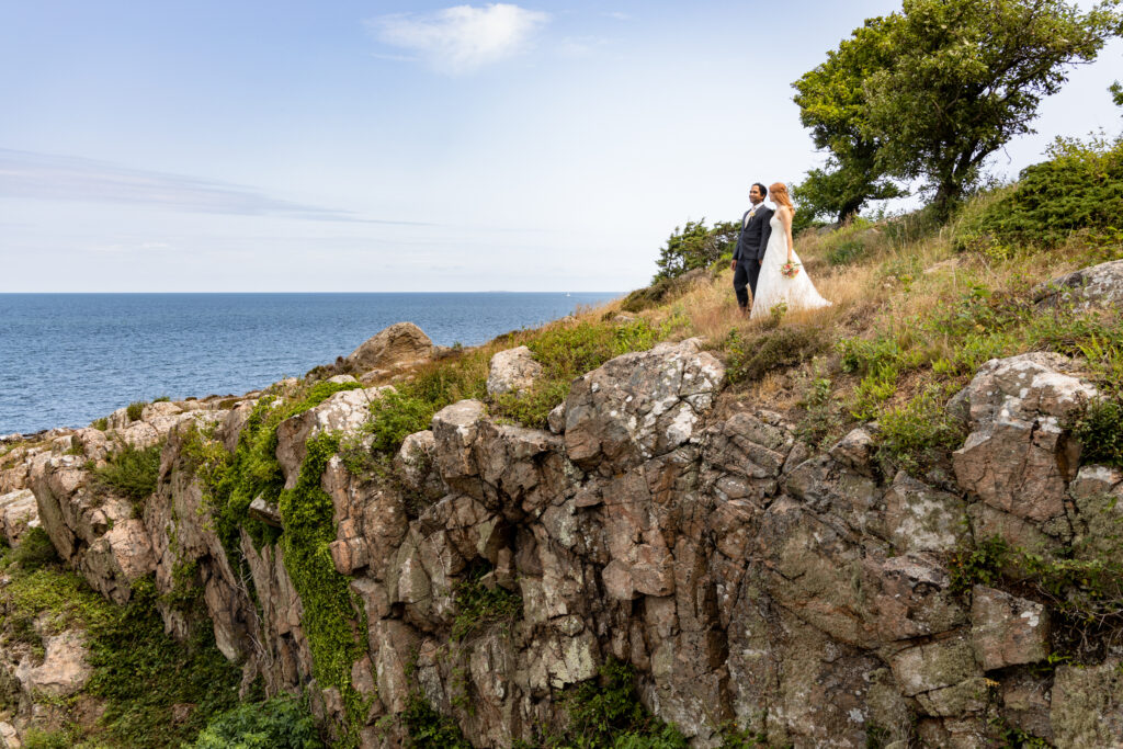 Newlyweds staying at the edge of cliffs on Bornholm island, where they have destination wedding in Europe.