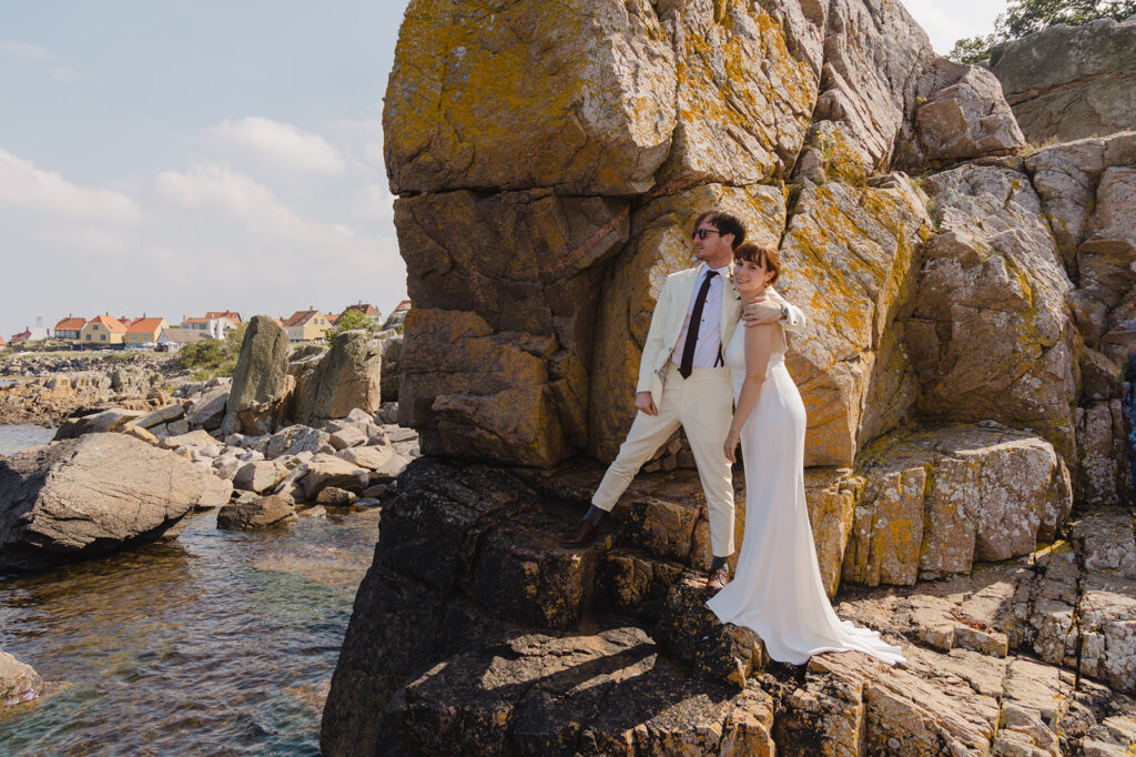 A couple posing on the rock after their adventure elopement to Bornholm island, one of best places in Europe for destination wedding