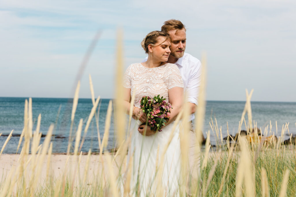 A couple embracing in thr meadow as they getting maried in Denmark.